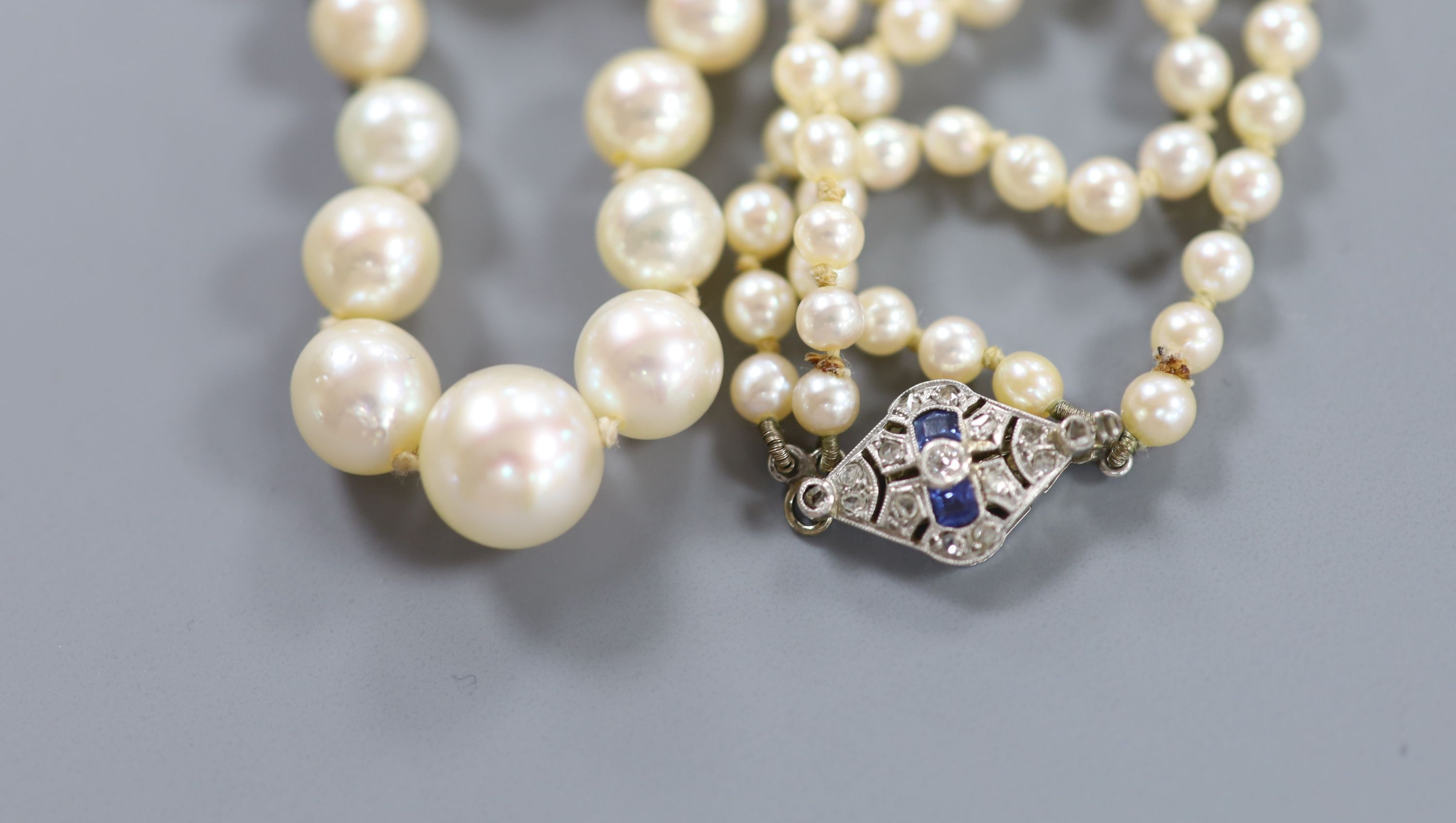 A double strand graduated cultured pearl necklace, with white metal (18ct poincon mark), sapphire and diamond set clasp signed Lacloche Freres and numbered 3763, 46cm, gross weight 33.8 grams